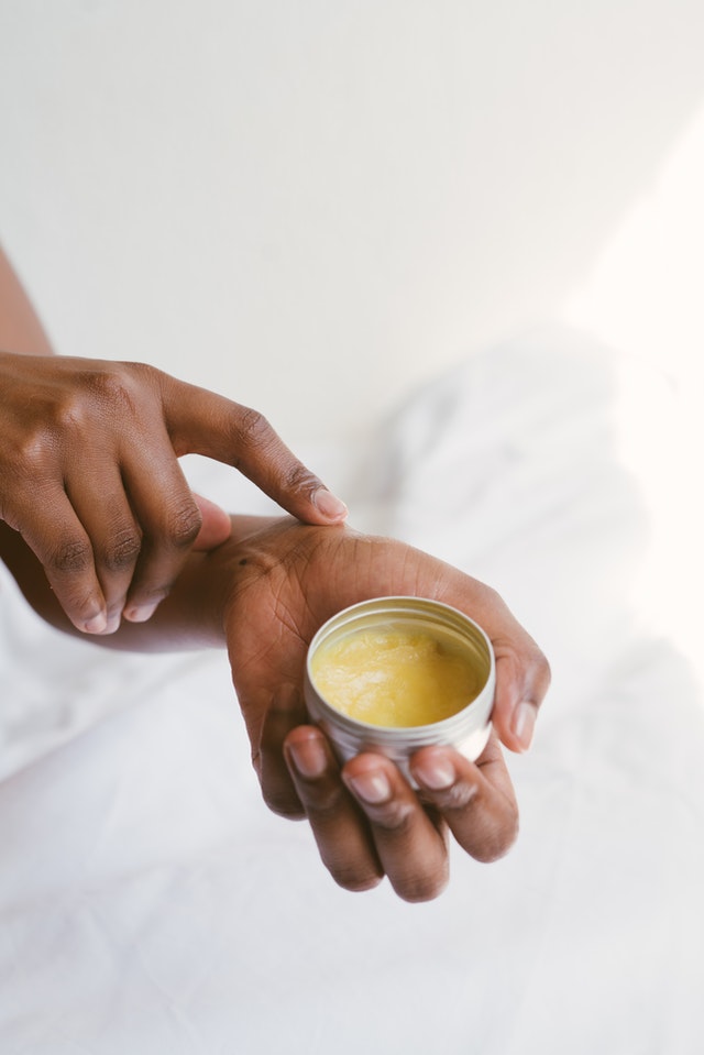 A person holding onto a jar of cream