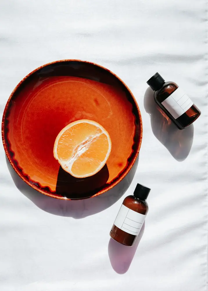 A bowl of orange and two bottles on the table.