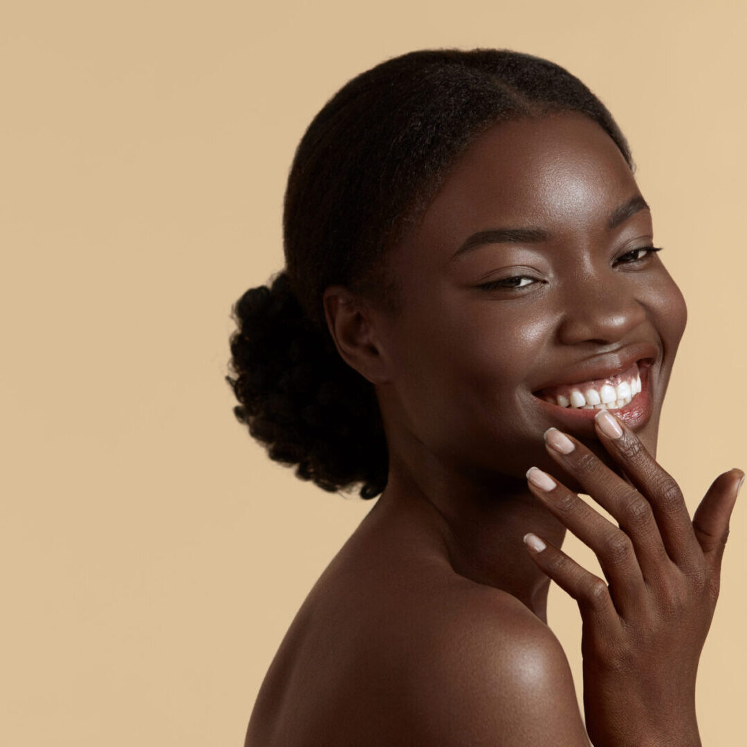 Beautiful african girl with perfect skin A woman smiling with her hand on her face.