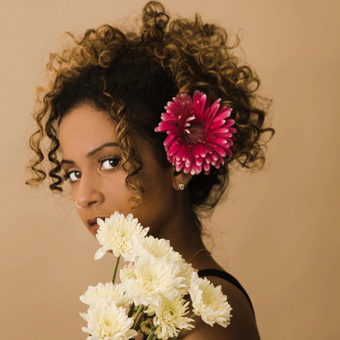 A woman with curly hair holding flowers in her hands.